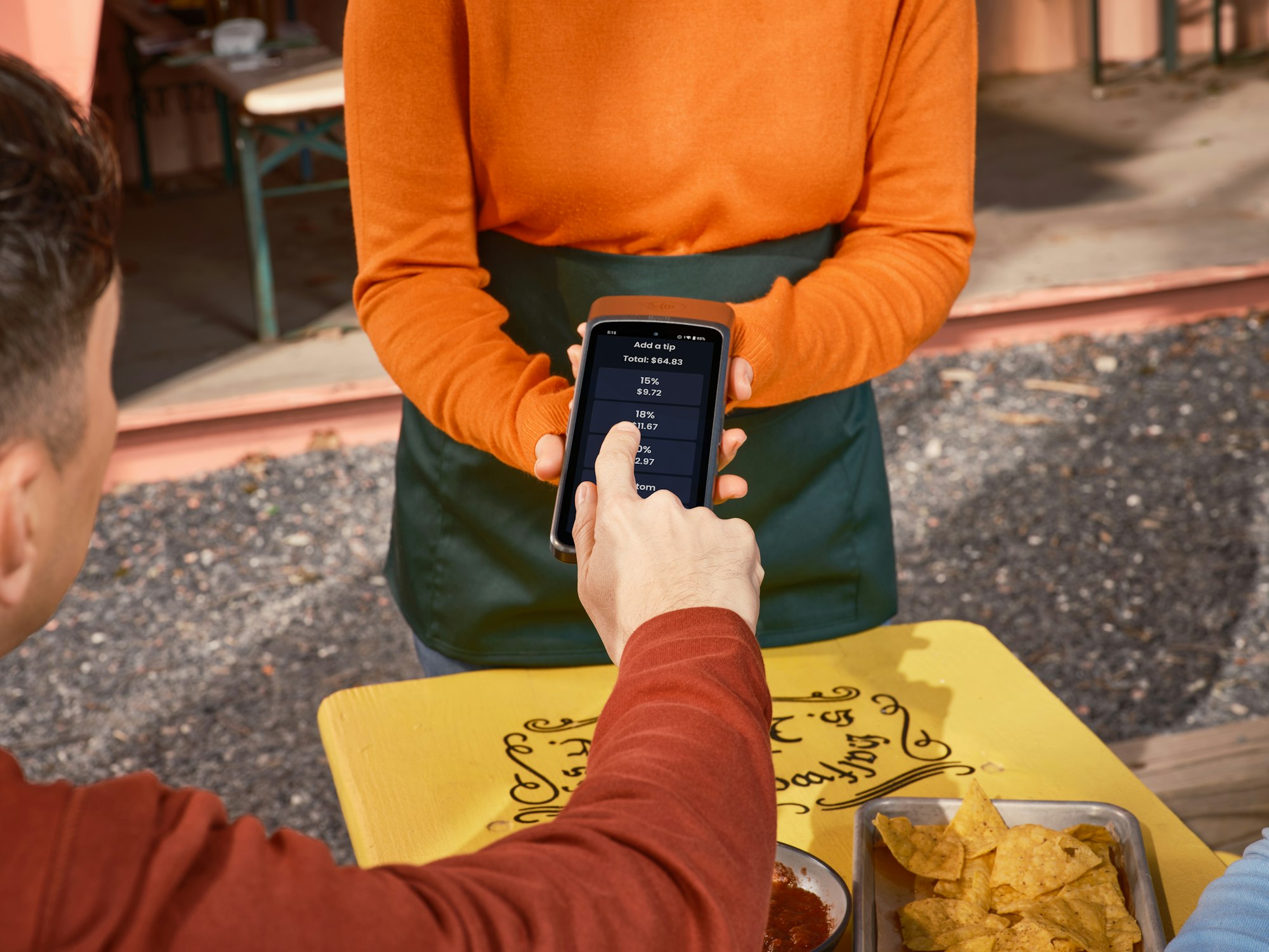 Someone paying with a phone at a cafe table